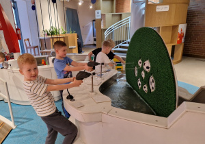 Chłopcy strzelają wodą do ruchomych piłek