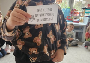 Dziewczynka prezentuje zadanie ułóż misie od największego do najmniejszego