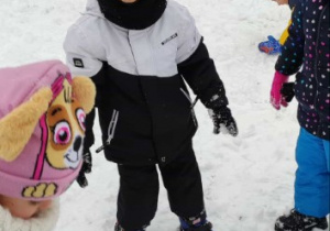 Chłpiec stoi z kulką śniegową w dłoni