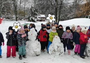 Dzieci pozują do zdjęcia z wykonanymi bałwanami