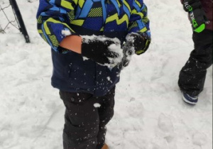 Chłopiec stoi ze śniegową kulką