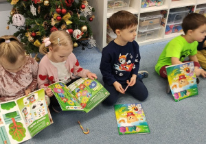 Dzieci siedzą na dywanie z upominkami