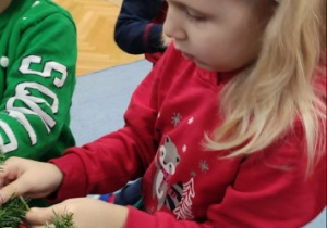 Dziewczynka zawiesza ozdobę na choince