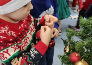 Chłopiec wiesza bombkę na choince