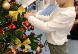 Chłopiec wiesza ozdobę na choince