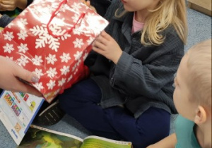 Dziewczynka sięga do torebki prezentowej i wyjmuje upominek