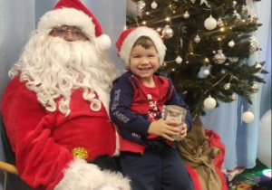 Chłopiec pozuje do zdjęcia z Mikołajem