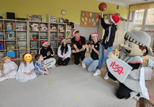 Dzieci podziwiają jak koszykarka kręci piłkę na palcu