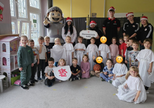 Dzieci z grupy Misie na wspólnym zdjęciu z koszykarzami, maskotką klubu i choinką