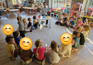 Dzieci siedzą w kole, pan psycholog pokazuje im książkę,