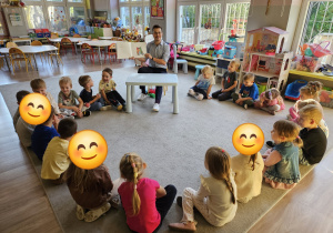 Dzieci siedzą w kole na dywanie.