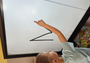 Chłopiec kreśli literę na tablicy