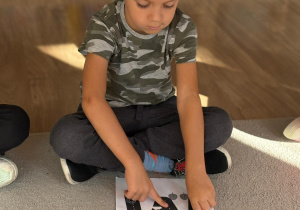 Chłopiec rysuje po śladzie literę