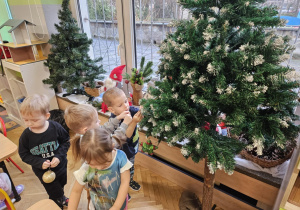 Dzieci zawieszają ozdoby na choinkę