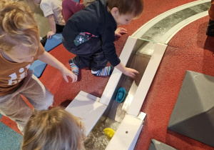 Dzieci bawią się łódkami przy torze wodnym