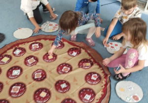 Dzieci bawią się z dużą matą pizzy