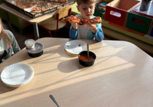 Chłopiec trzyma w rękach kawałek pizzy