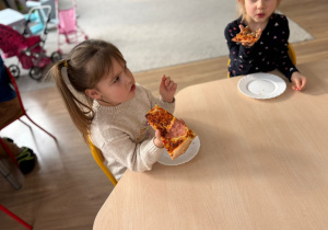 Dziewczynka trzyma kawałek pizzy