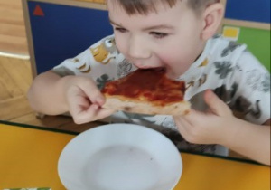 Chłopiec gryzie kawałek pizzy