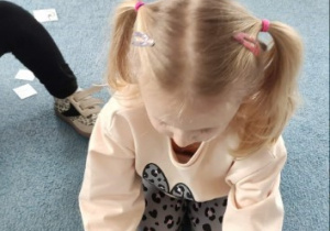 Dziewczynka układa składniki na krążku pizzy do zabawy