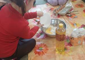 Dziewczynka wsypuje mąke do miski