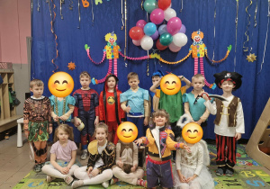 Dzieci w strojach na tle dekoracji na balu karnawałowym