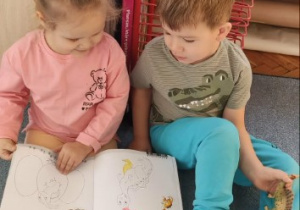 Dziewczynka i chłopiec oglądają książkę