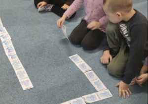 Dzieci siedzą na dywanie grają w grę - Ja mam dinozaura który ... Kto ma dinozaura który ...