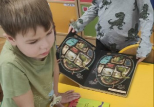 Chłopcy oglądają książki o dinozaurach