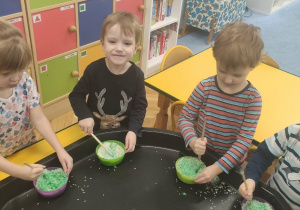 Dzieci mieszają ryz z farbą w miseczkach