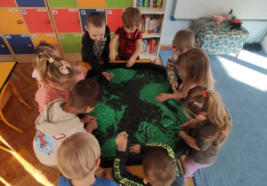 Dzieci bawią się kolorowym ryżem i dinozaurami