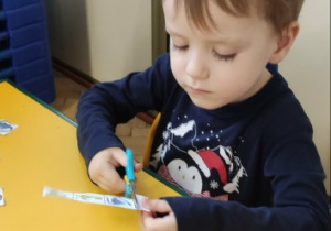 Chłopiec posługuje się nożyczkami