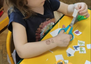 Dziewczynka wycina elementy do gry z kodowaniem