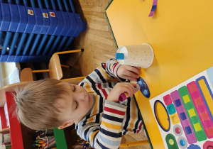 Chłopiec przykleja elementy do kubeczka