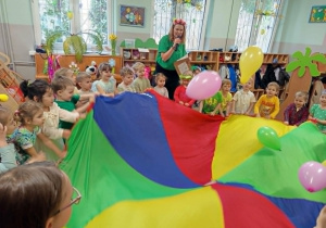 Dzieci bawią się chustą animacyjna , podrzucają balony
