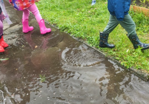 Dzieci w kaloszach chodzą po kałużach