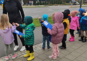 Grupa dzieci stoi na chodniku przy ulicy