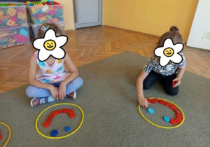 Dwie dziewczynki układają uśmiech z klocków w kolorowym kółku